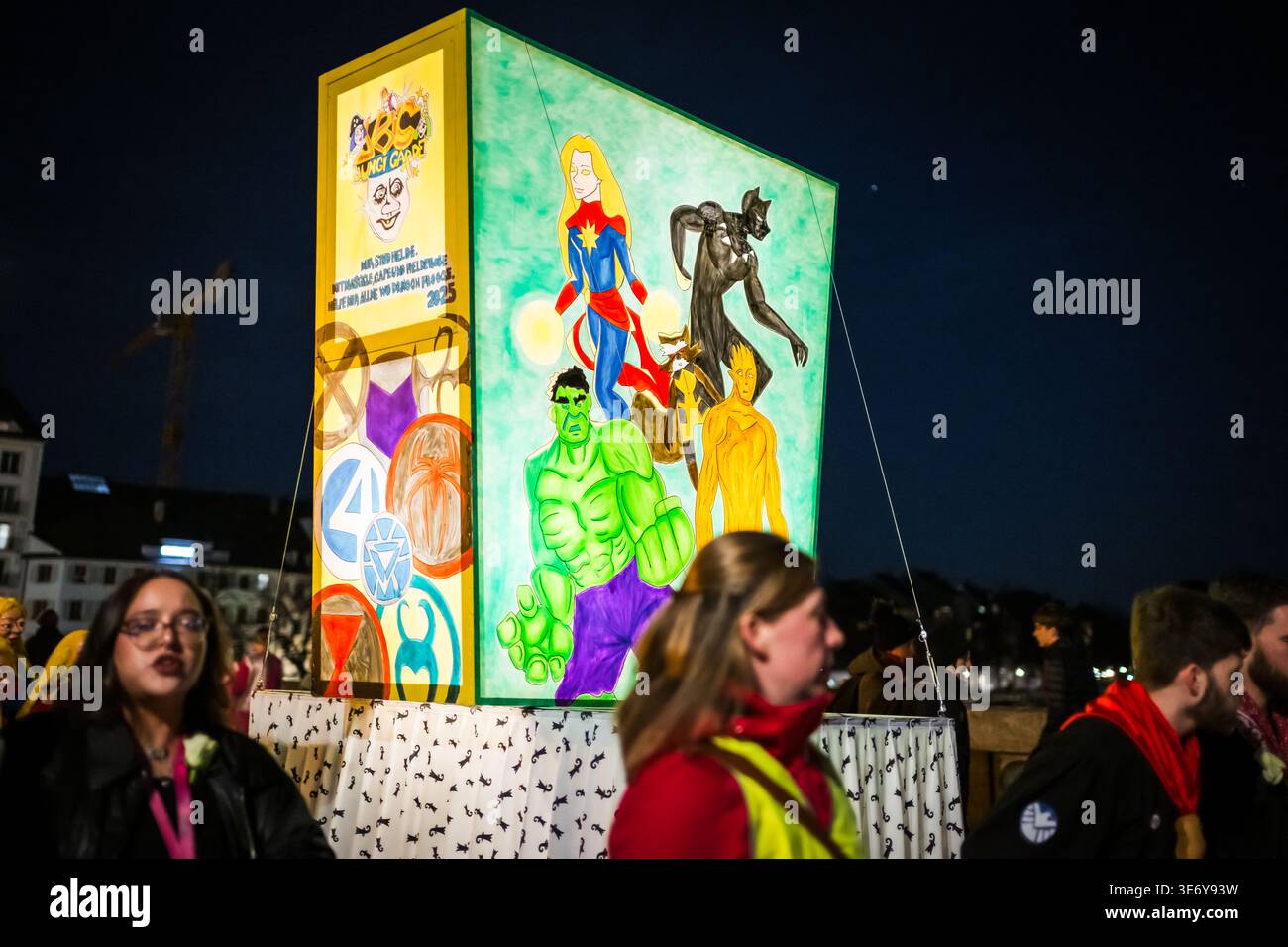 Bâle, Suisse - 10 mars 2025 : vue d'un flotteur lumineux vibrant avec des personnages de bandes dessinées à Fasnacht, projetant une lueur surréaliste sur le ni Banque D'Images