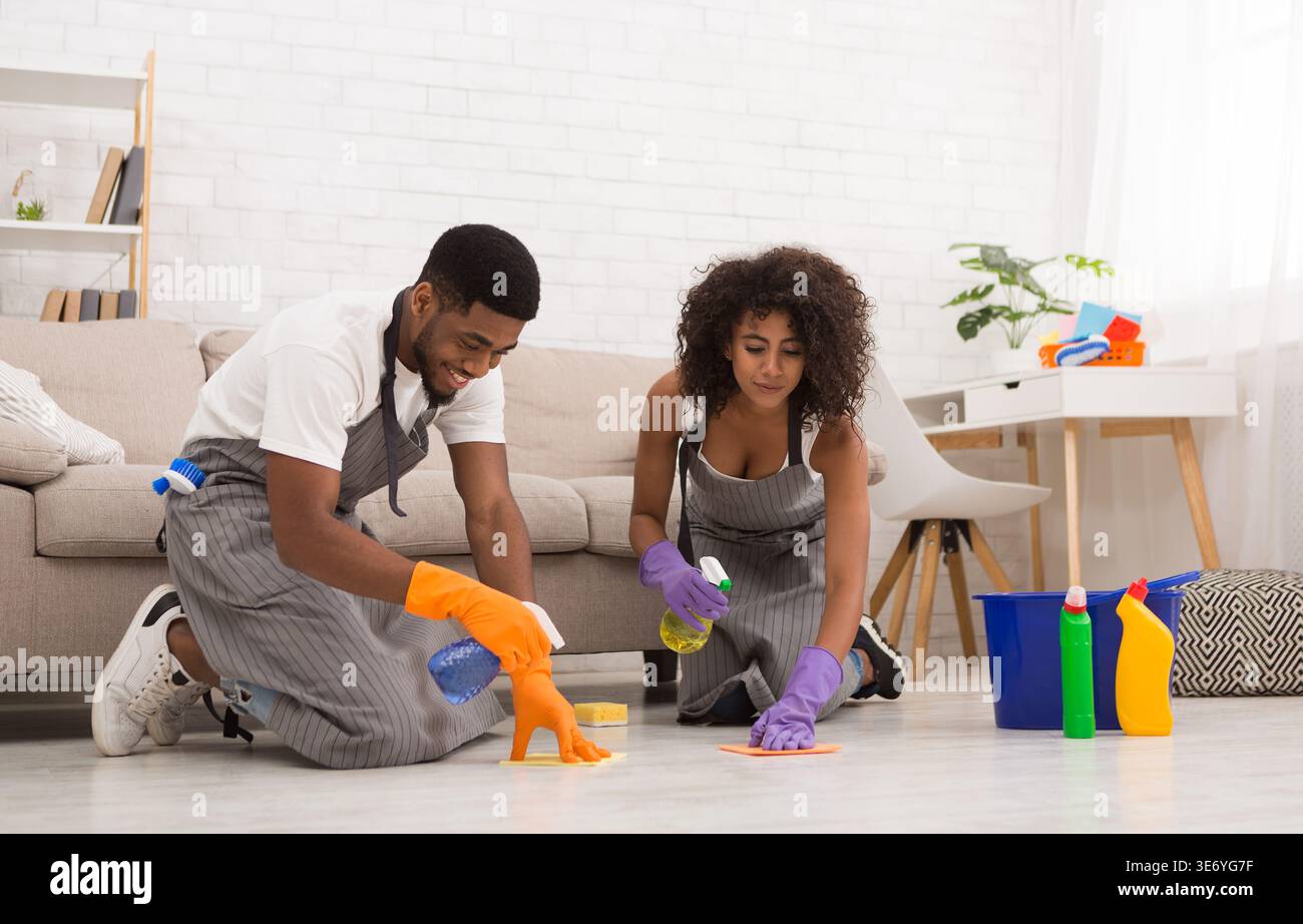 Plancher de lavage jeune couple avec serviette et spray Banque D'Images