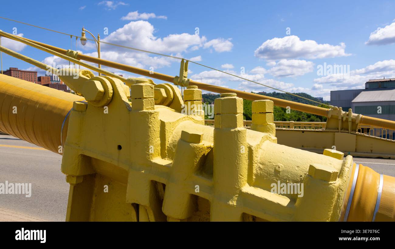 Détails structuraux jaunes d'un pont montrant des boulons, des connexions et des câbles épais contre un ciel bleu à Pittsburgh Banque D'Images