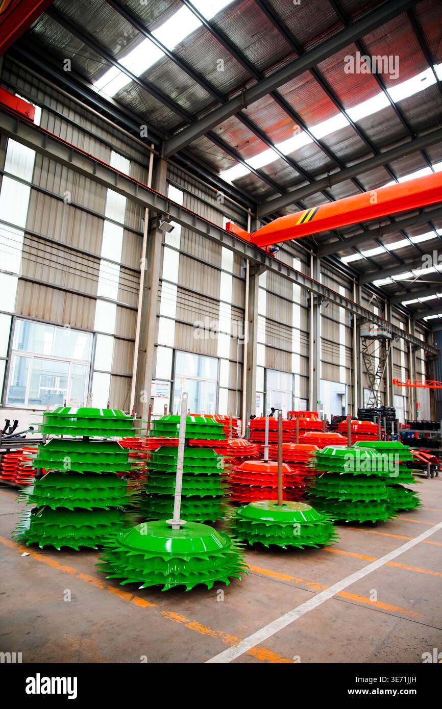 Les disques de coupe rotatifs des machines agricoles soigneusement empilés dans l'atelier de l'usine sont principalement vert vif, et le même type de p rouge Banque D'Images