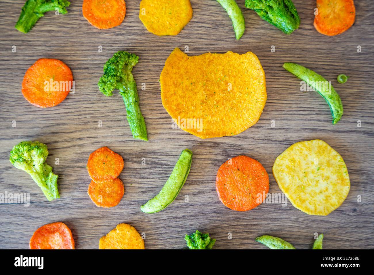 Modèle sans couture de chips de légumes avec des pois carottes brocoli et de la patate douce sur fond en bois. Texture de collation saine et concept de consommation propre. Banque D'Images