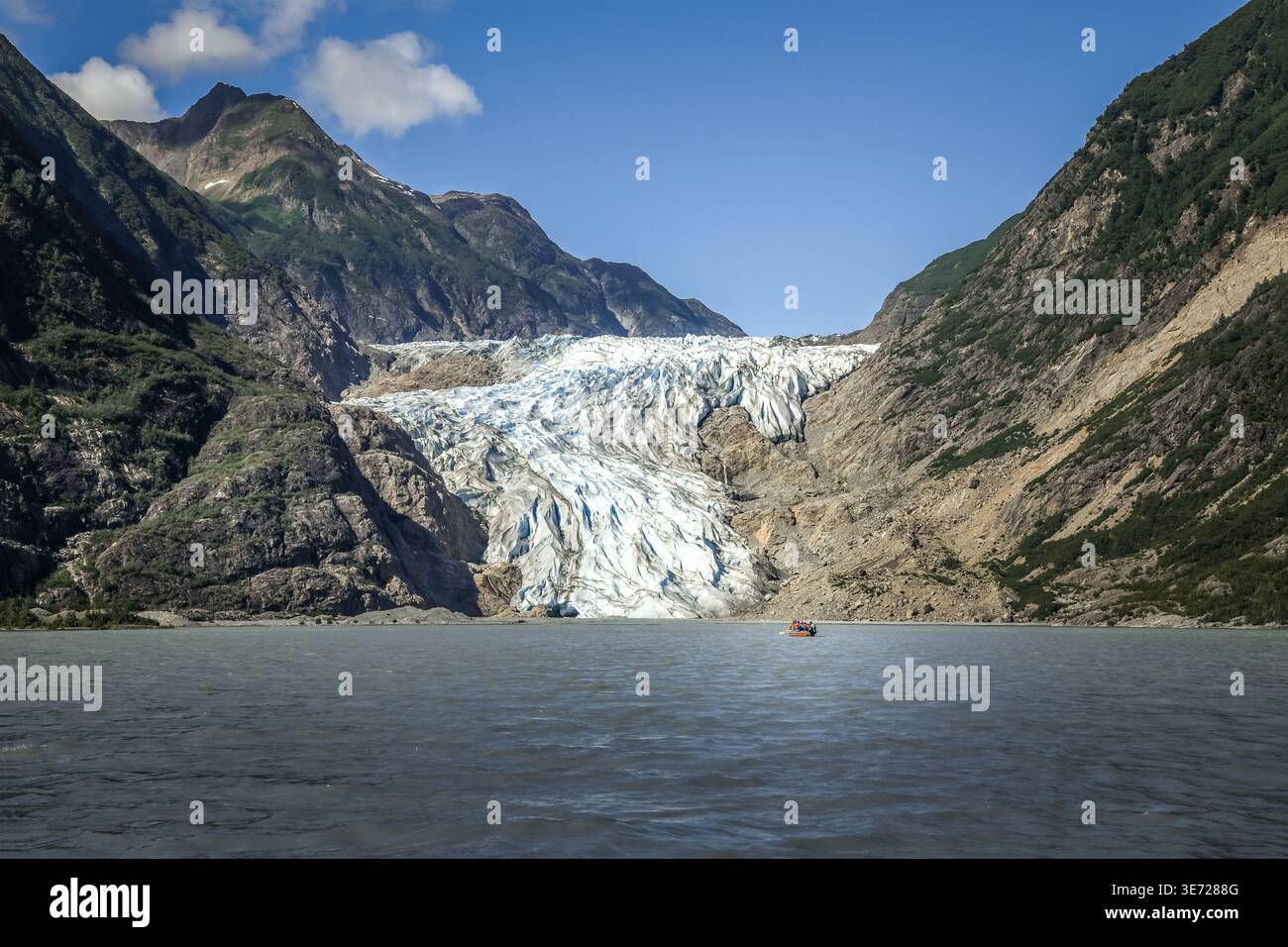 Énorme glacier Chilkat en Alaska surplombant les eaux tranquilles du fjord avec un petit canoë au premier plan Banque D'Images