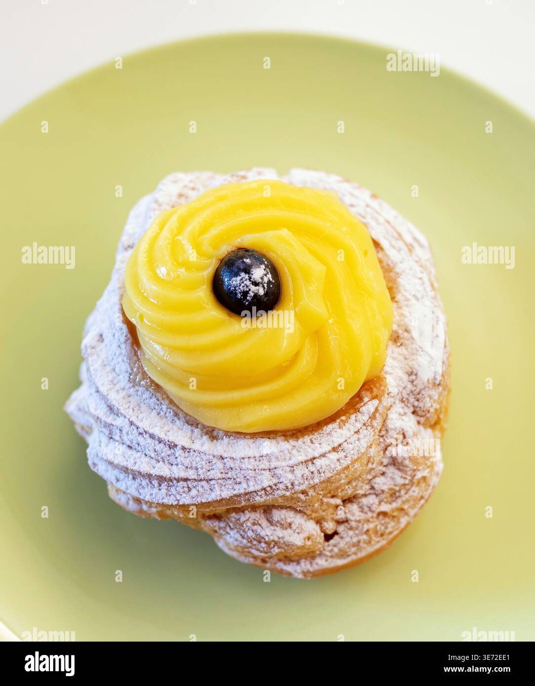Zeppole di San Giuseppe, desserts traditionnels à base de choux italiens, avec un anneau moelleux, un tourbillon de crème anglaise riche et une cerise noire foncée sur le dessus, saupoudrée de sucre en poudre pour la célébration de la fête de Joseph Banque D'Images