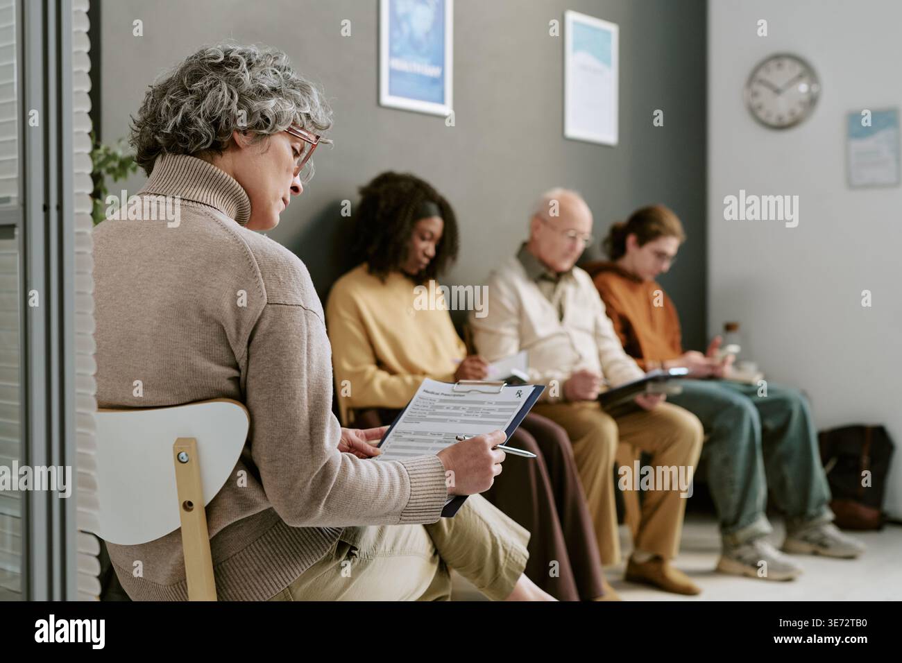 Femme âgée remplissant le formulaire d'admission dans la salle d'attente médicale Banque D'Images