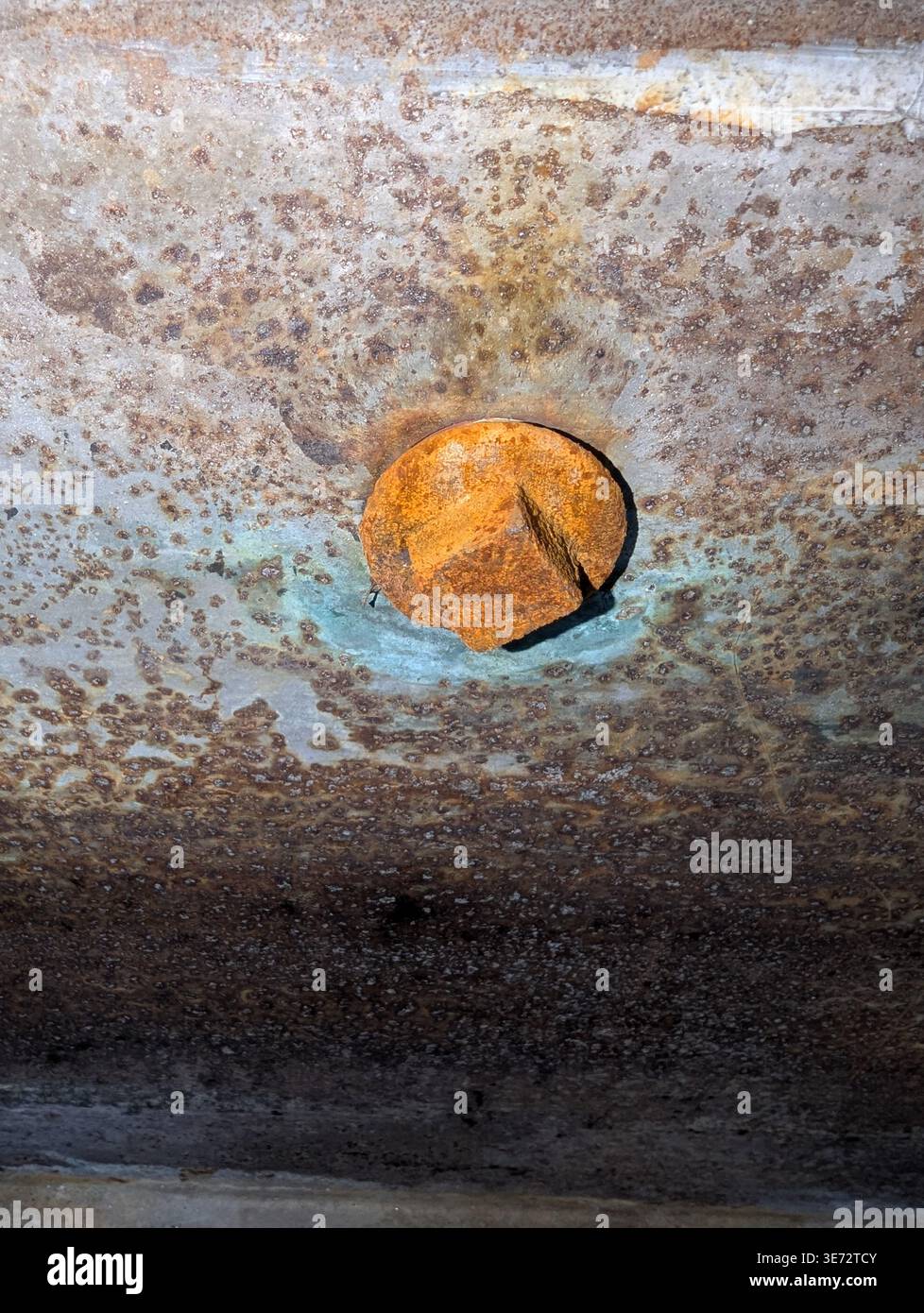 Boulon rouillé en cours d'inspection sur métal peint, gros plan révélant un halo bleu et des revêtements écaillés des convoyeurs vérification d'entretien, entretien Banque D'Images