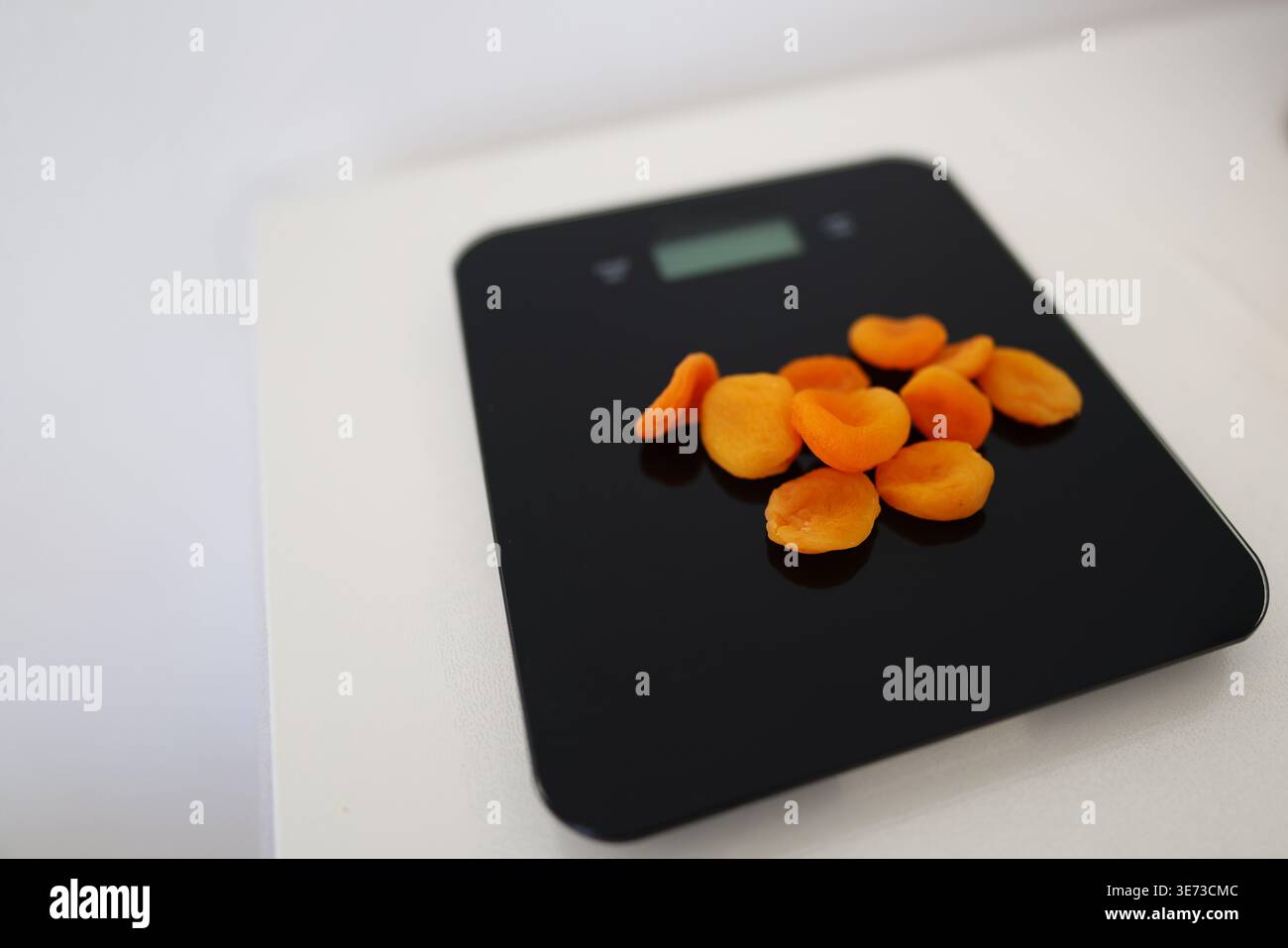 Mesure des abricots séchés sur balance électronique, nutrition et concept de comptage des calories. Banque D'Images