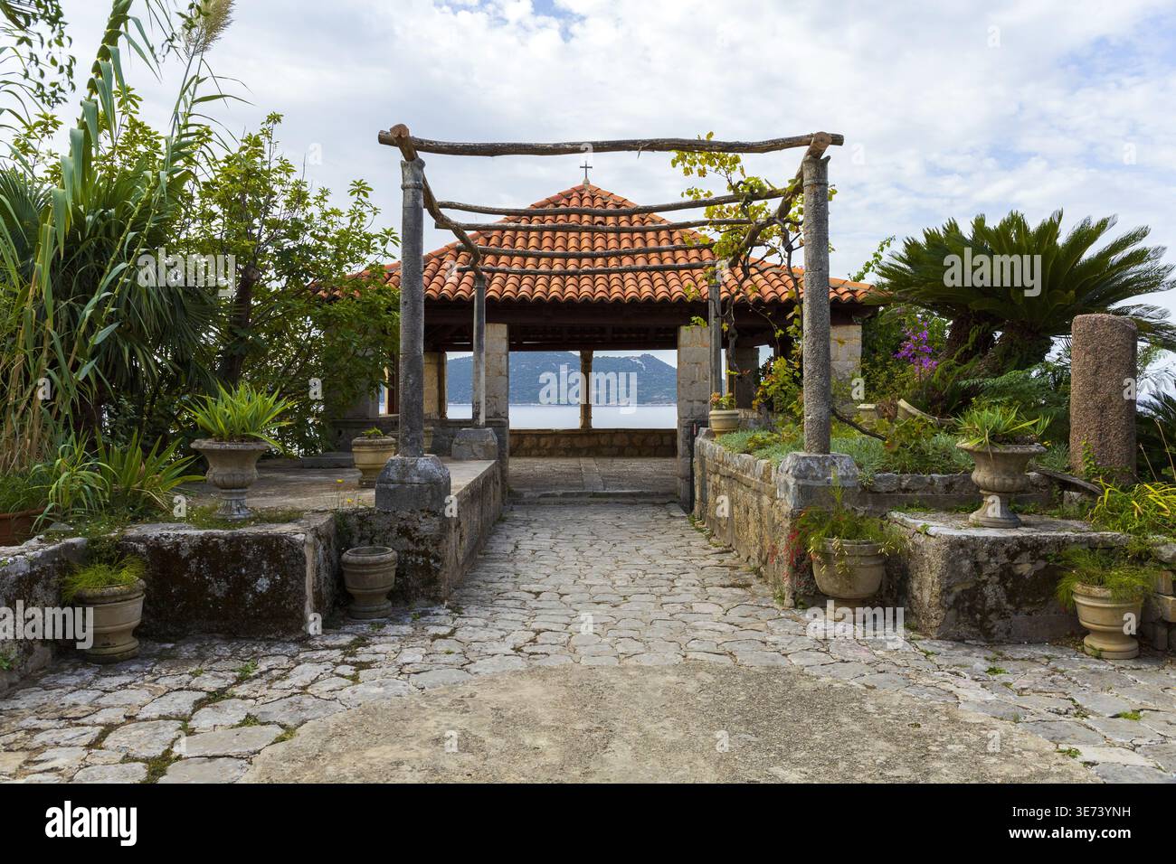Pavillon de jardin en pierre avec vue sur la mer encadré par des plantes et des allées. Composition symétrique dans le jardin méditerranéen. Banque D'Images