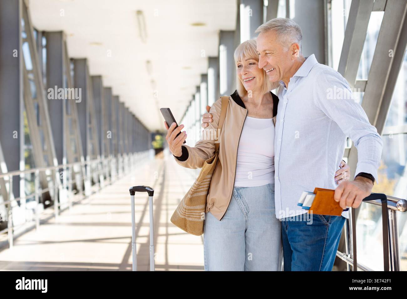 Couple mûr penché sur la garde-corps de l'aéroport regardant un smartphone ensemble Banque D'Images