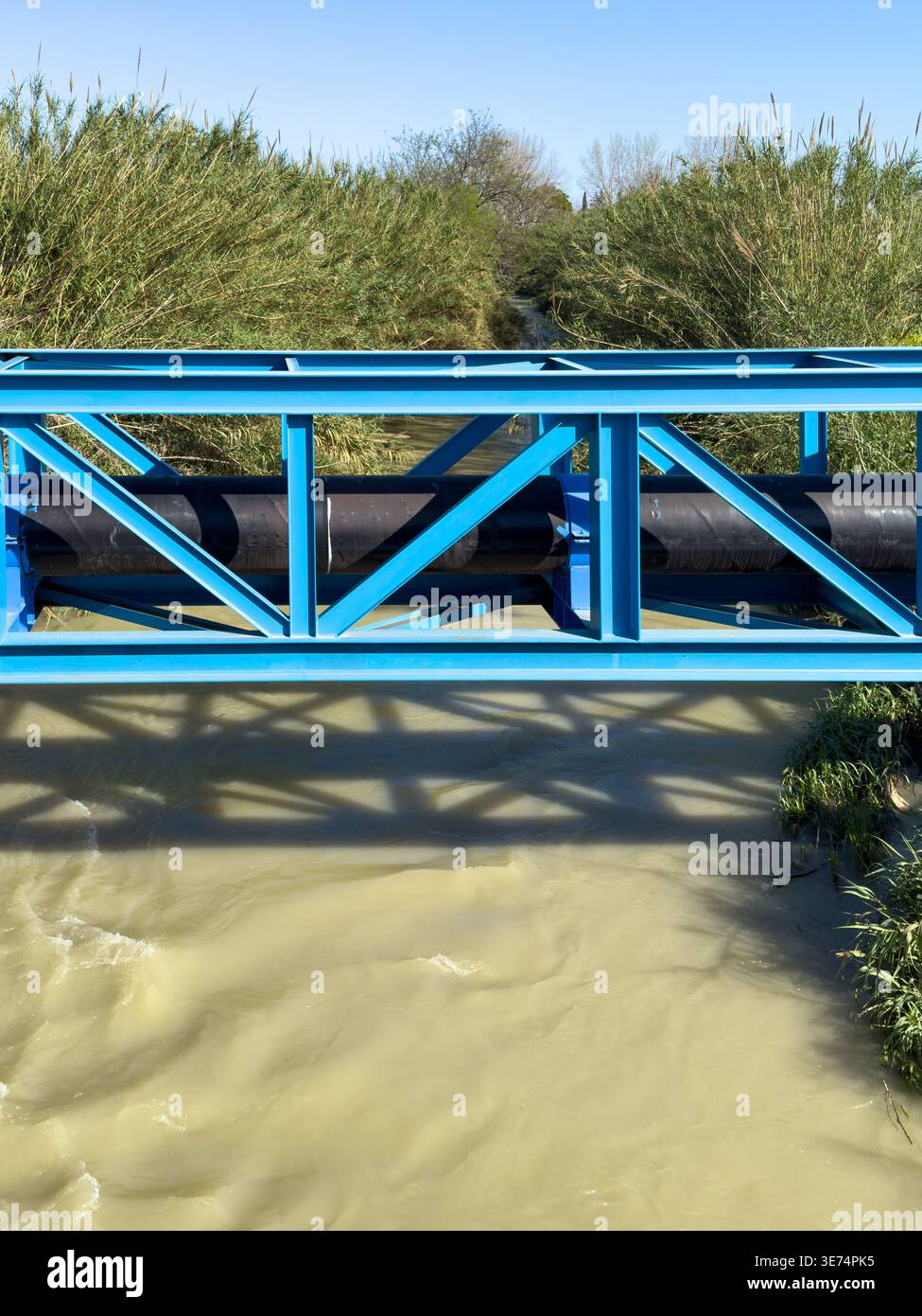 Pont de pipeline industriel au-dessus de l'eau représentant l'infrastructure, le débit et la distribution des ressources Banque D'Images