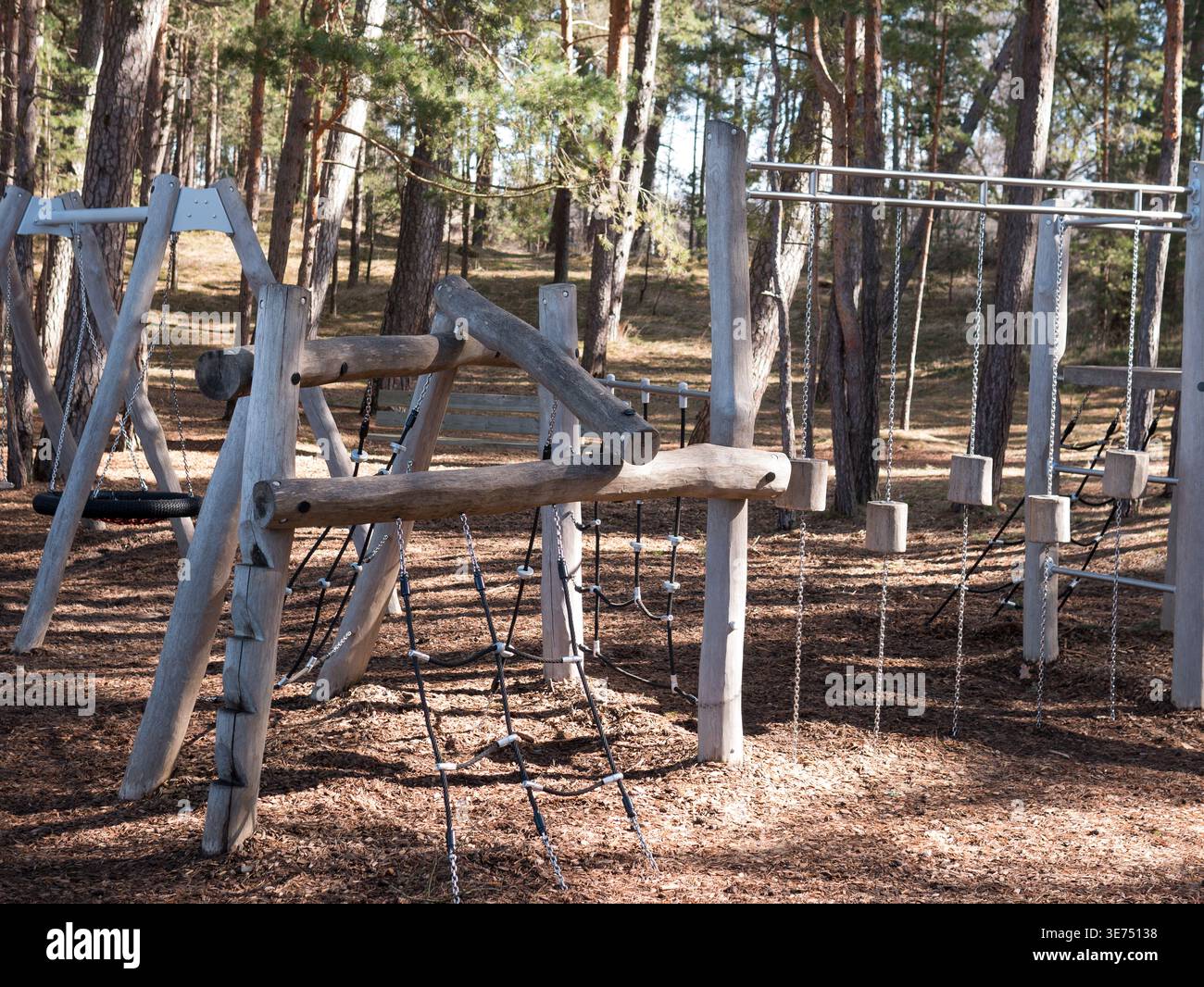 Aire de jeux extérieure en bois vide dans la forêt de pins — aire de jeux naturelle pour enfants au début du printemps Banque D'Images