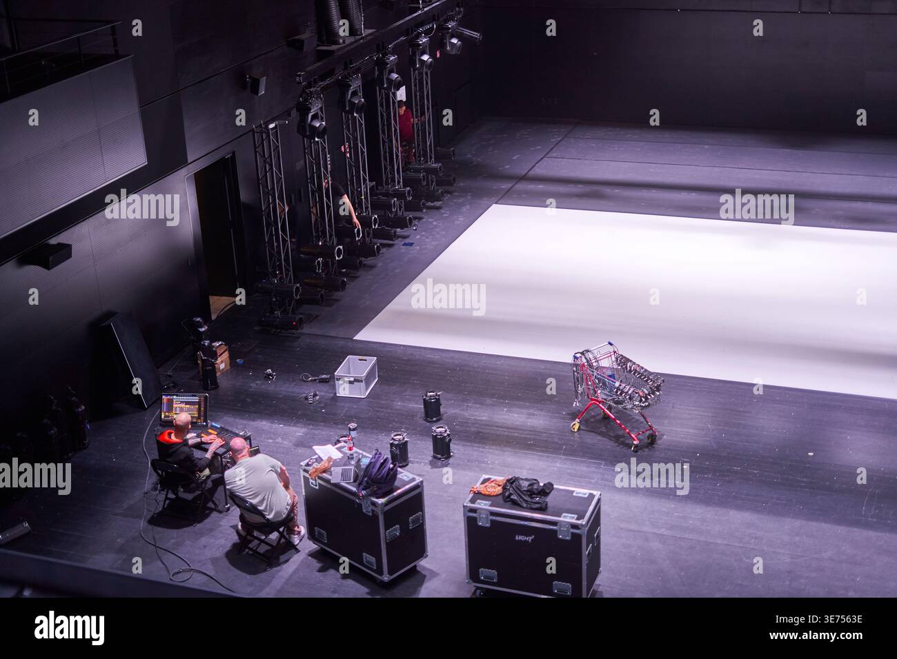 Vue en hauteur d'intérieur d'un théâtre ou lieu de spectacle moderne pendant la préparation technique. Deux techniciens utilisent des équipements informatiques à un bureau dans le Banque D'Images