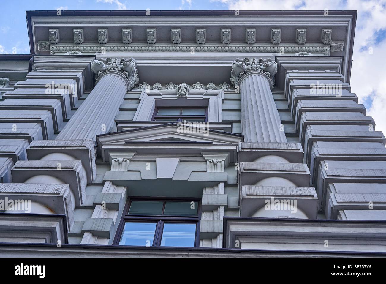 Une vue basse et ascendante d'une façade de bâtiment néo-classique ornée mettant en valeur des éléments architecturaux classiques. Deux corinthiennes canonnées proéminentes Banque D'Images
