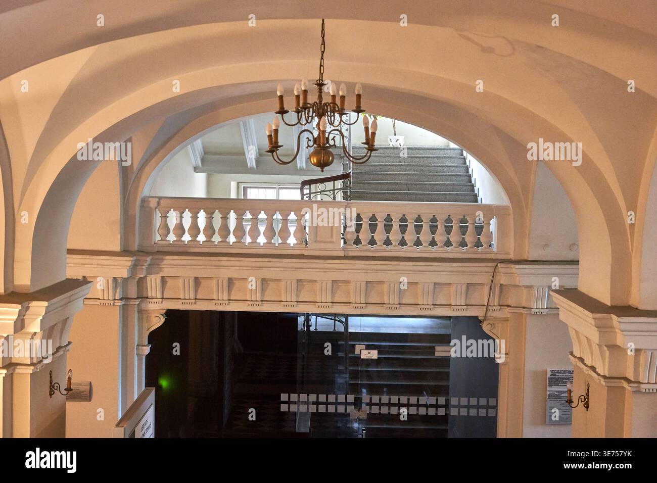 L'image capture un espace architectural intérieur élégant présentant des éléments de design classique. Un grand lustre en laiton orné de style bougie Banque D'Images