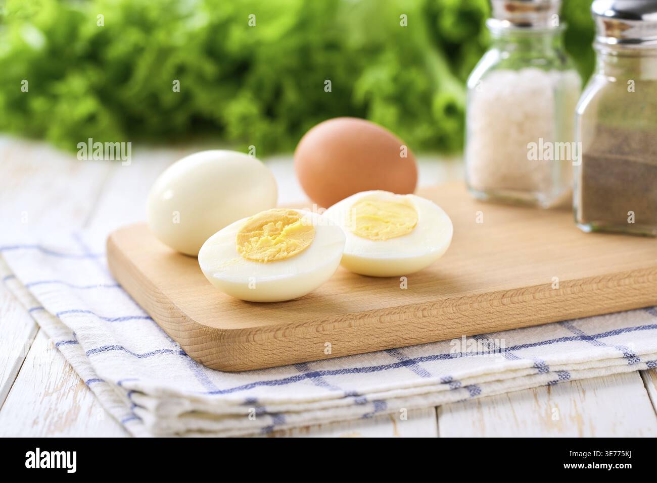 Oeufs durs pelés et coupés en deux avec du sel et du poivre sur une table blanche, mise au point sélective Banque D'Images