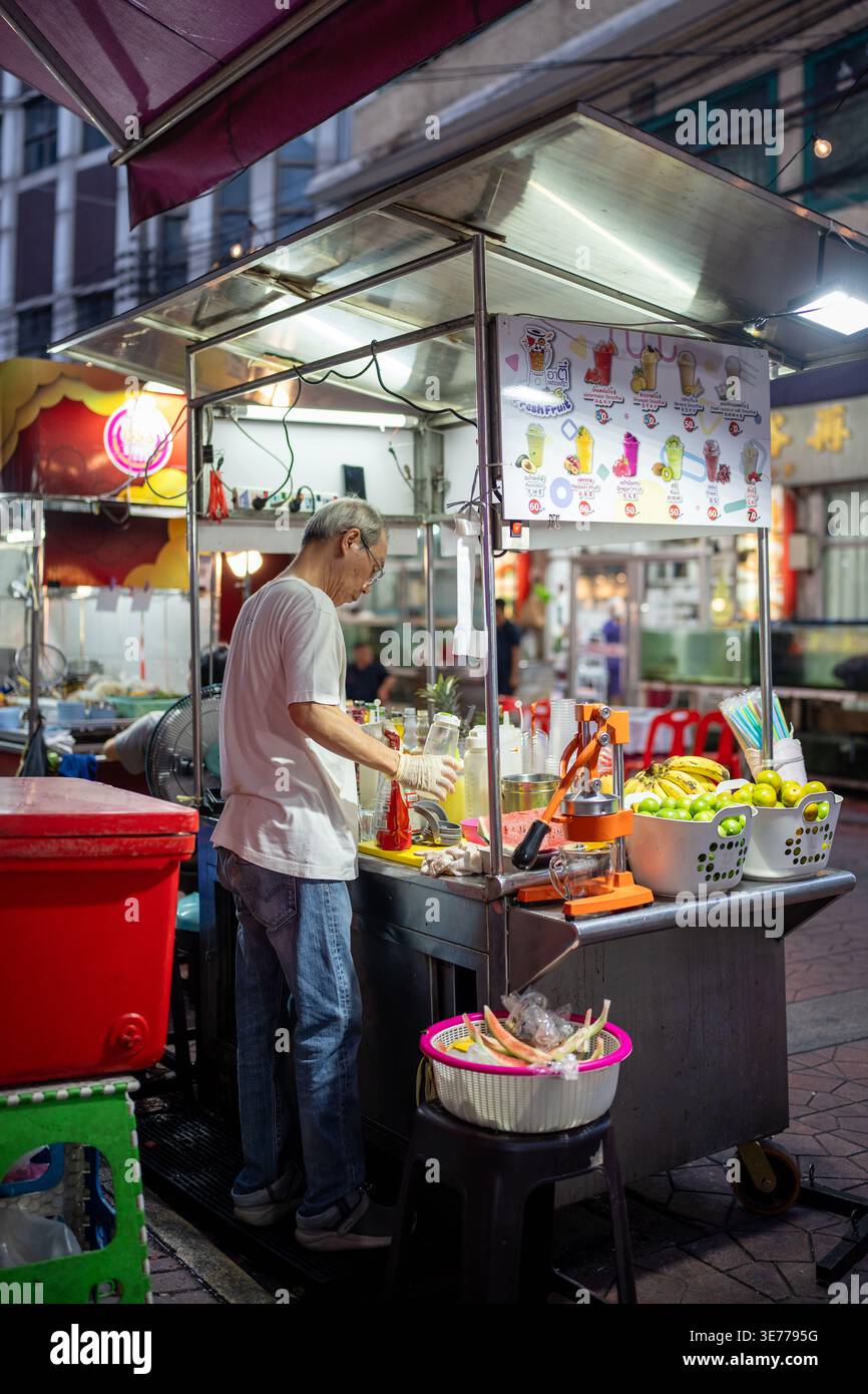 Vendeur fabriquant et vendant des jus de fruits fraîchement pressés, des smoothies et des boissons aux fruits au marché de rue local. Banque D'Images