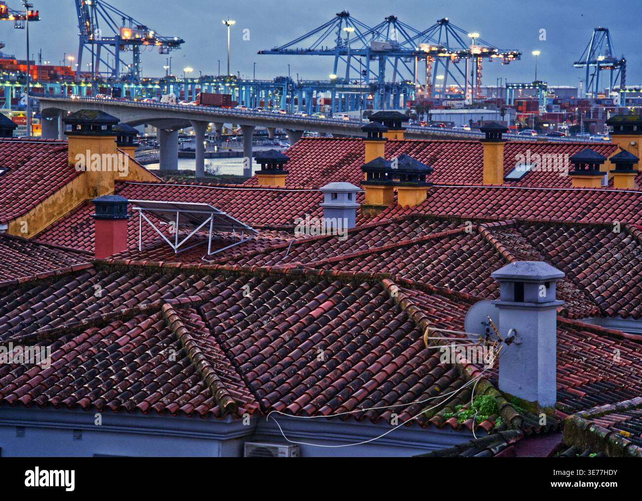 Port industriel d'Algeciras et pont moderne avec un trafic mobile dominant en arrière-plan sur les toits espagnols traditionnels avec des cheminées et un solaire Banque D'Images