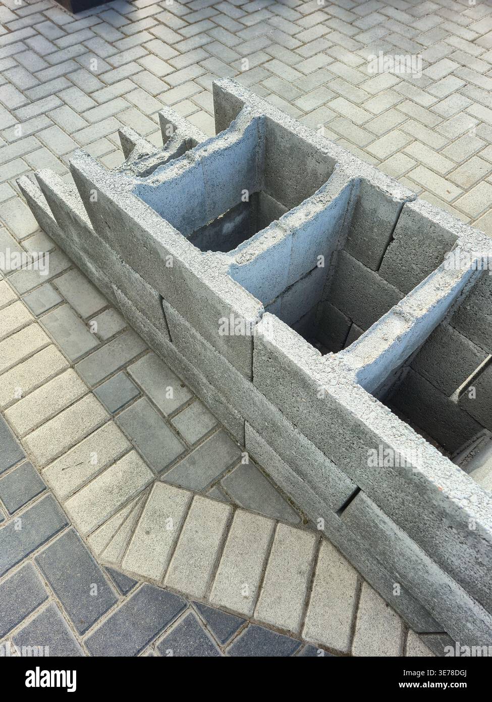 Une vue rapprochée de blocs de béton creux assemblés sur un patio pavé à motifs, suggérant un projet de construction ou d’aménagement paysager en cours Banque D'Images