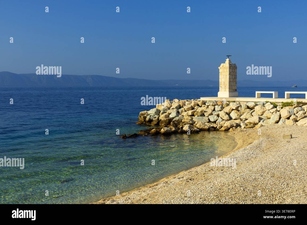 Petit phare sur la jetée rocheuse avec mer Adriatique claire. Point de repère côtier en Croatie Banque D'Images