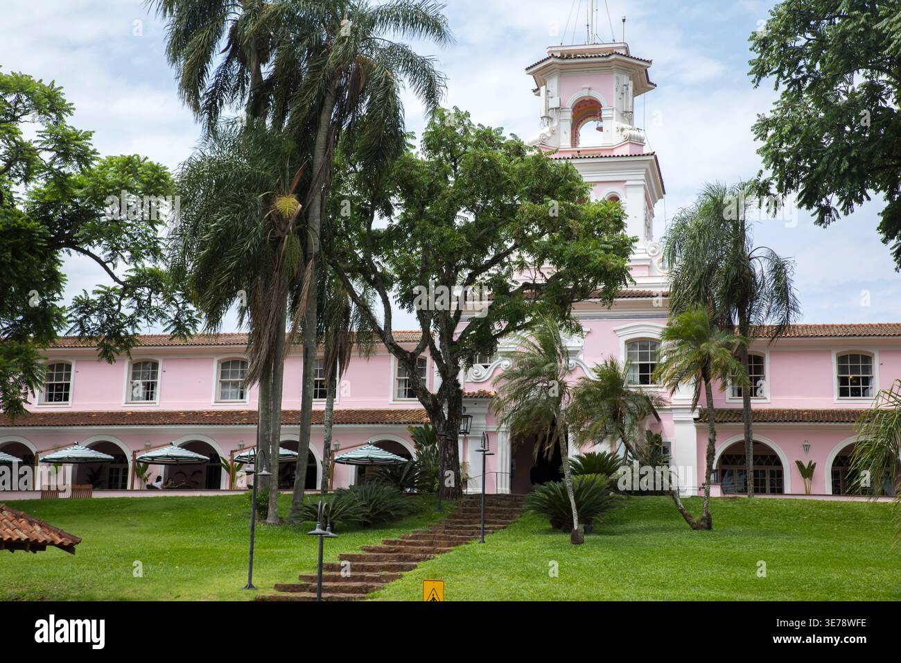 Un majestueux bâtiment rose de style colonial avec un clocher blanc distinctif se dresse bien en vue au milieu d'une végétation tropicale luxuriante à Foz do Iguacu, Paraná, Br Banque D'Images