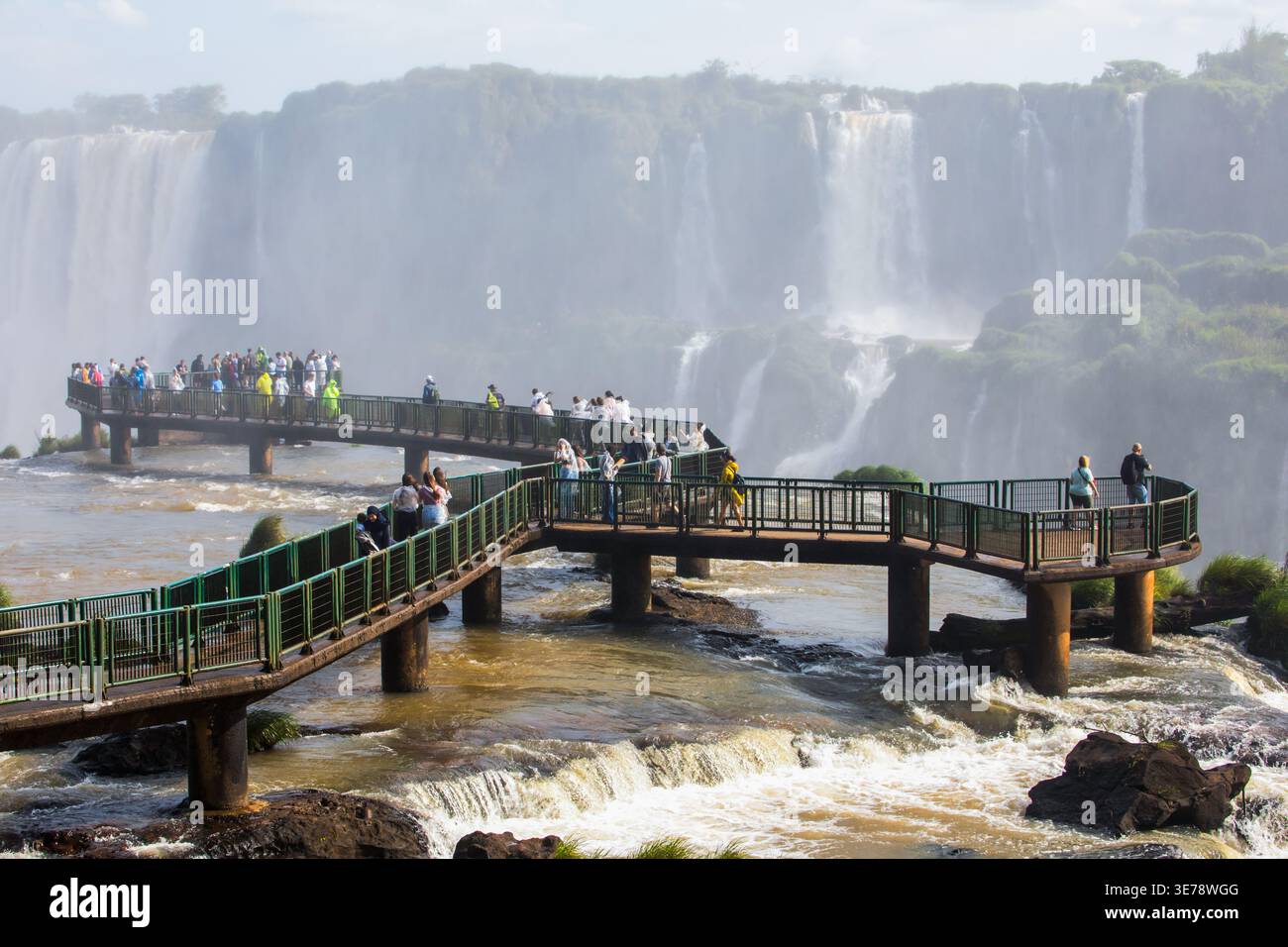 Des dizaines de touristes se rassemblent sur les passerelles métalliques surélevées qui s'étendent sur les eaux turbulentes des chutes d'Iguazu, l'une des plus grandes et des plus spectacu du monde Banque D'Images