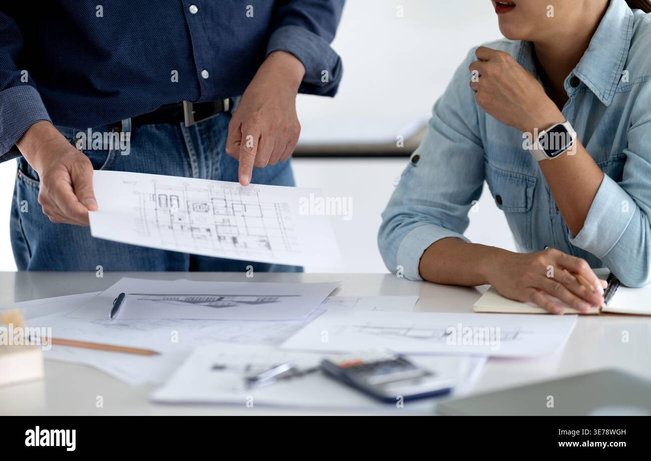 L'architecte ou l'ingénieur examine et vérifie les détails de la conception du bâtiment pour voir si elle répond aux objectifs de planification de l'administrateur Banque D'Images