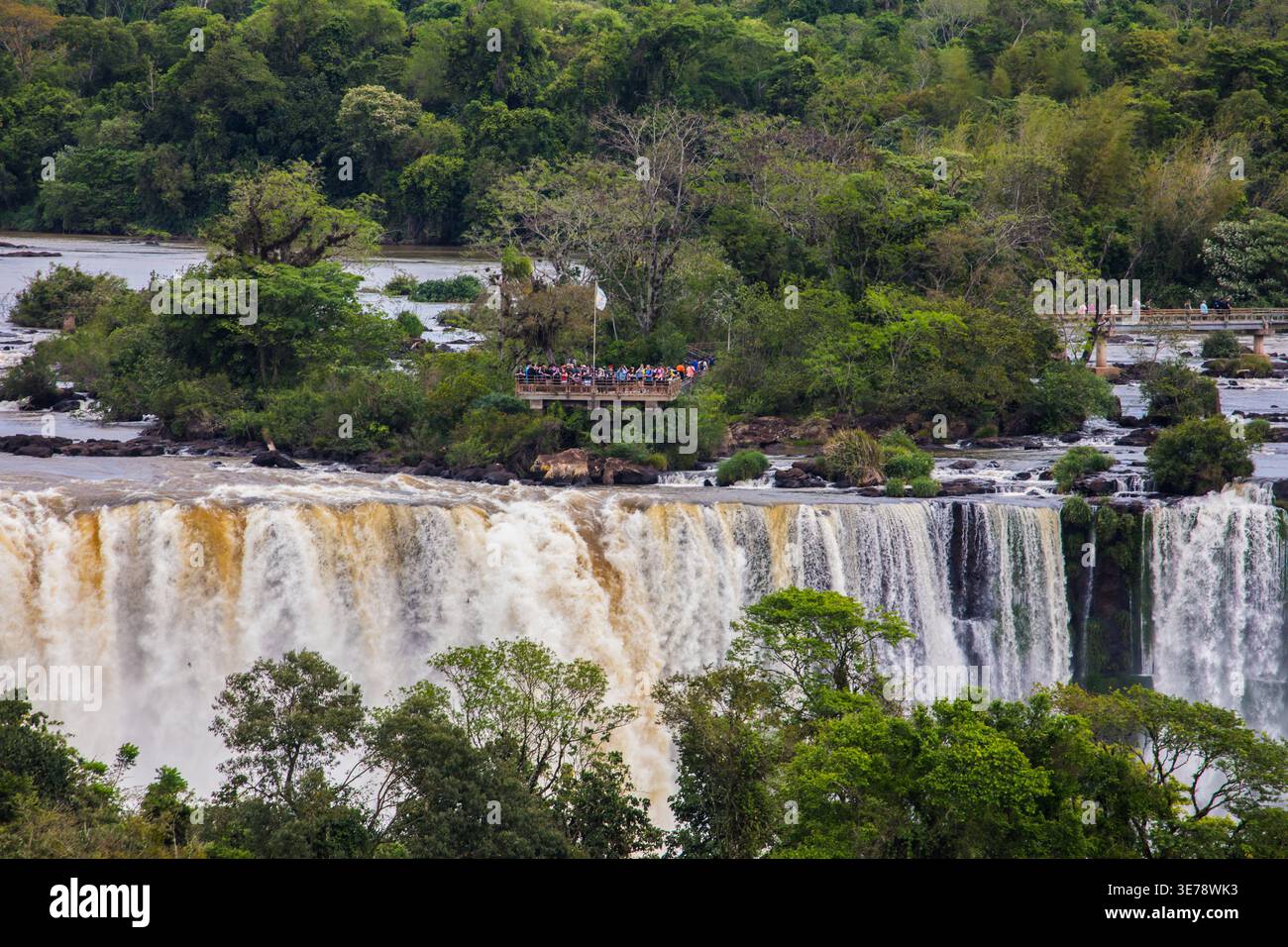 Touristes sur la plate-forme d'observation dans le côté argentin. Les spectaculaires chutes d'Iguazu descendent plusieurs niveaux de formations rocheuses de basalte couvertes de tanières Banque D'Images