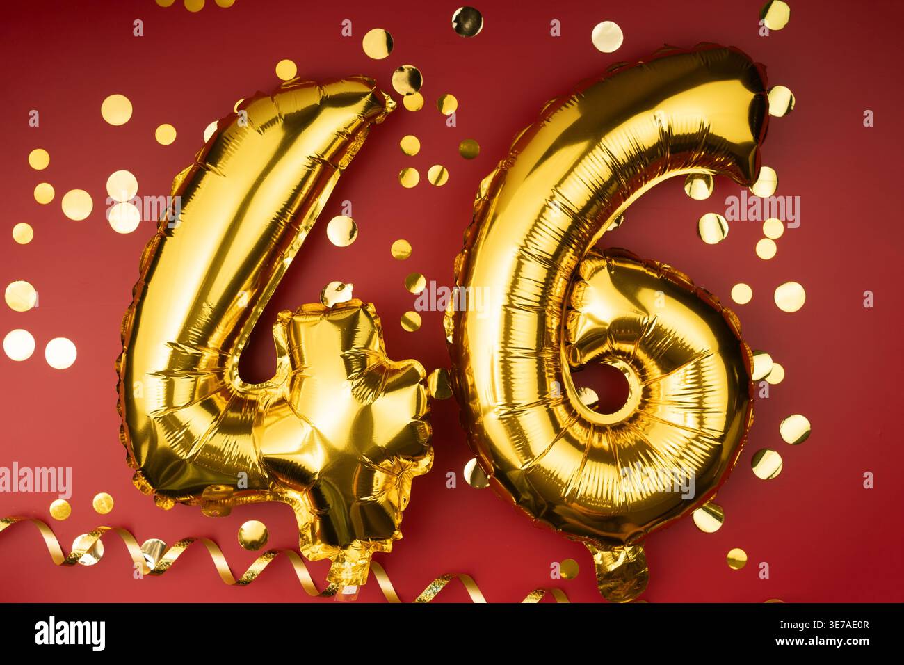 célébration du 46e anniversaire. Ballons festifs dorés numéro 46 anniversaire sur fond rouge avec des confettis. Anniversaire ou mariage. Banque D'Images