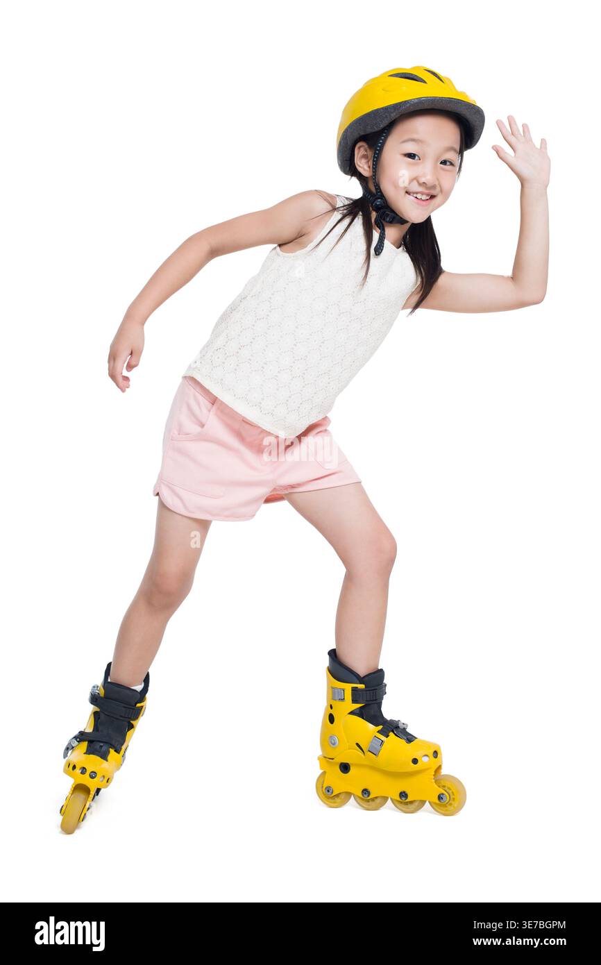 Jeune fille chinoise joyeuse portant un casque agitant la main tout en patinant à roulettes sur fond blanc dans le studio Banque D'Images