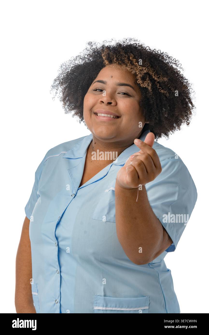Femme hispanique de grande taille avec afro bouclé portant un uniforme bleu faisant coeur avec des doigts debout sur fond blanc dans le studio Banque D'Images