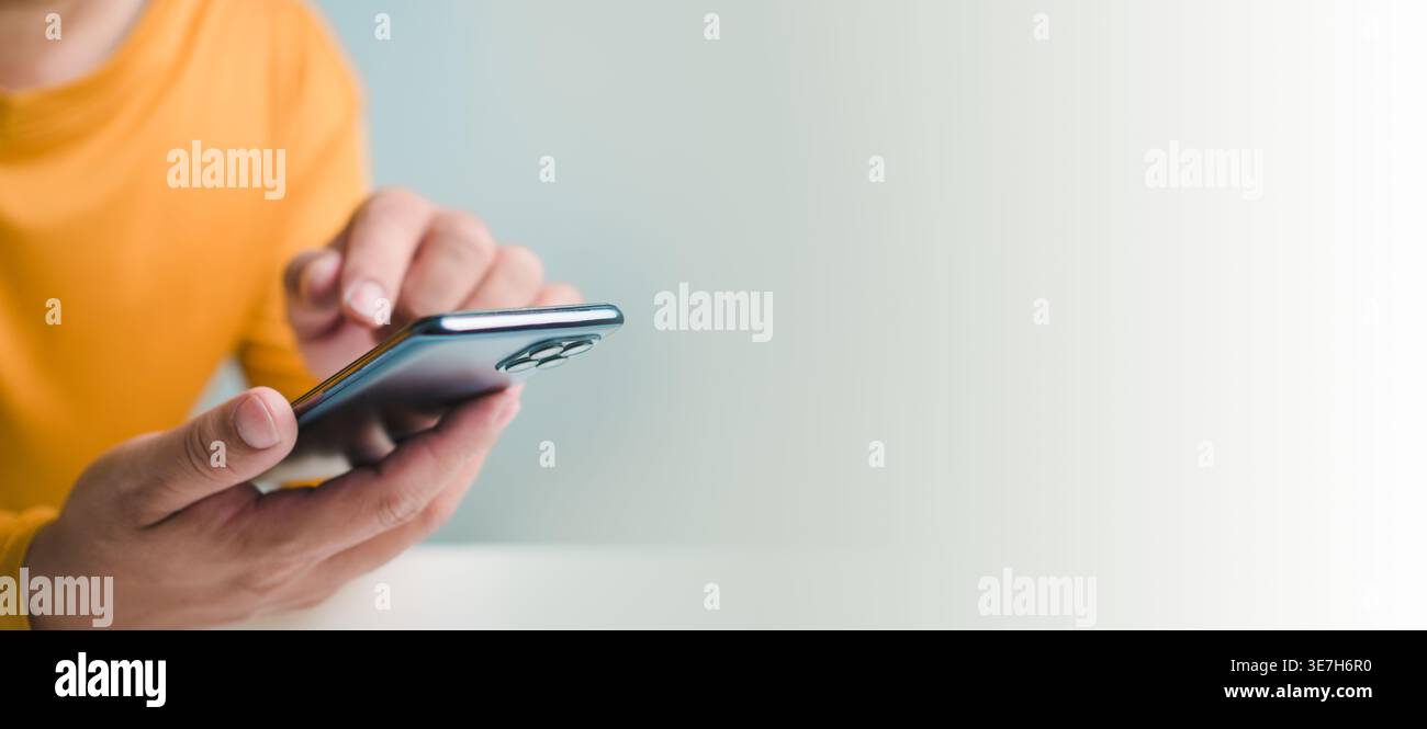 Image recadrée de l'homme utilisant un smartphone devant un mur blanc Banque D'Images