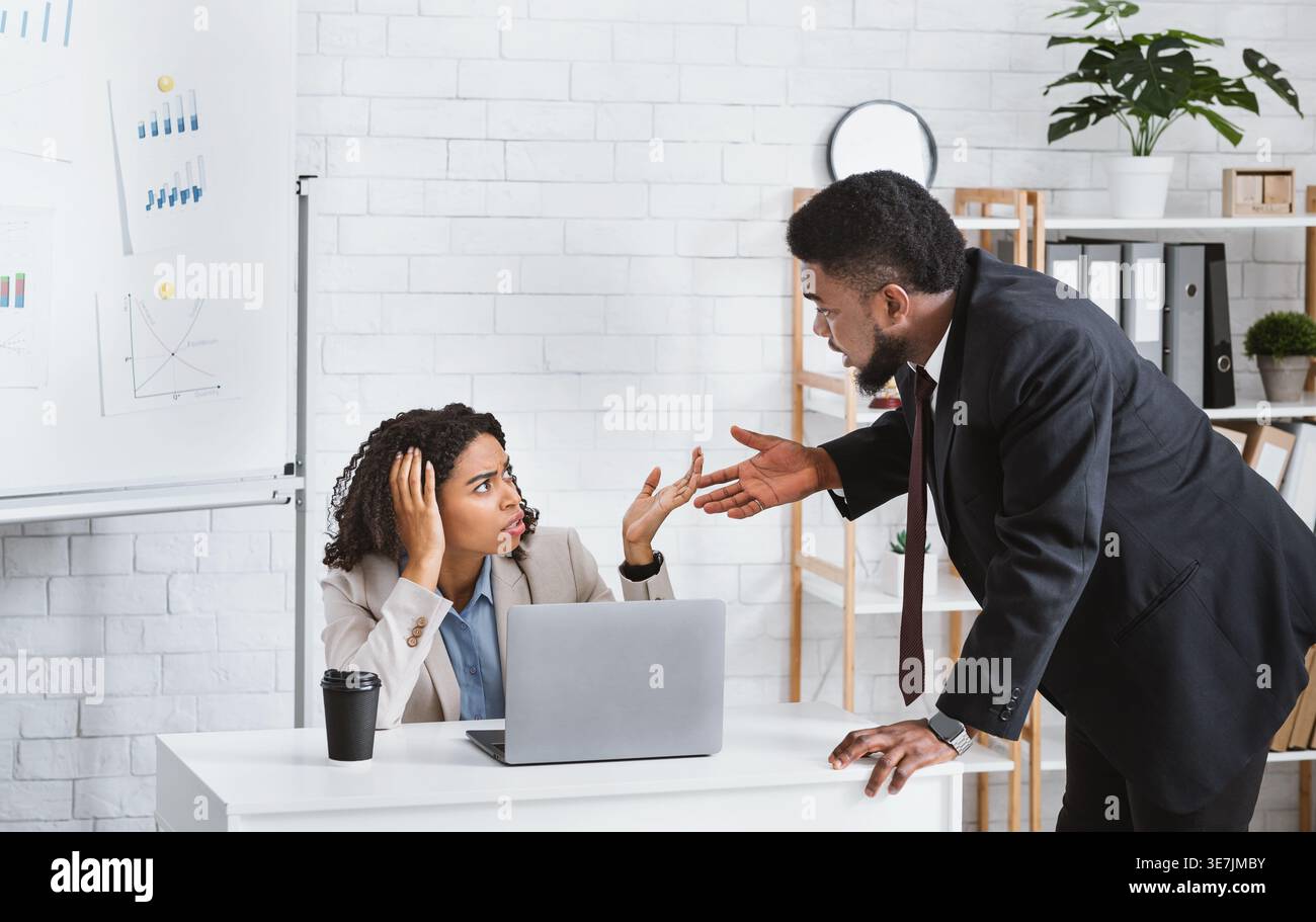 Employés noirs masculins et féminins se confrontant pendant le travail au bureau Banque D'Images