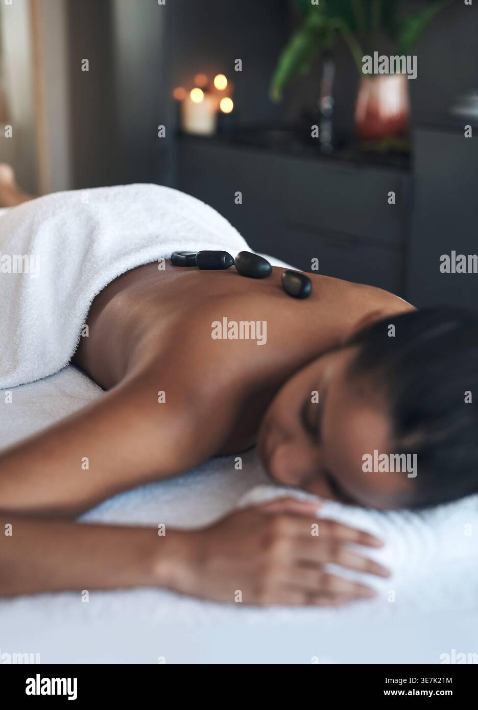Femme, se détendre et masser avec des pierres au spa pour la paix, la tension musculaire et la guérison des tissus profonds. Personne féminine, sommeil et thérapie thermique avec chaud Banque D'Images