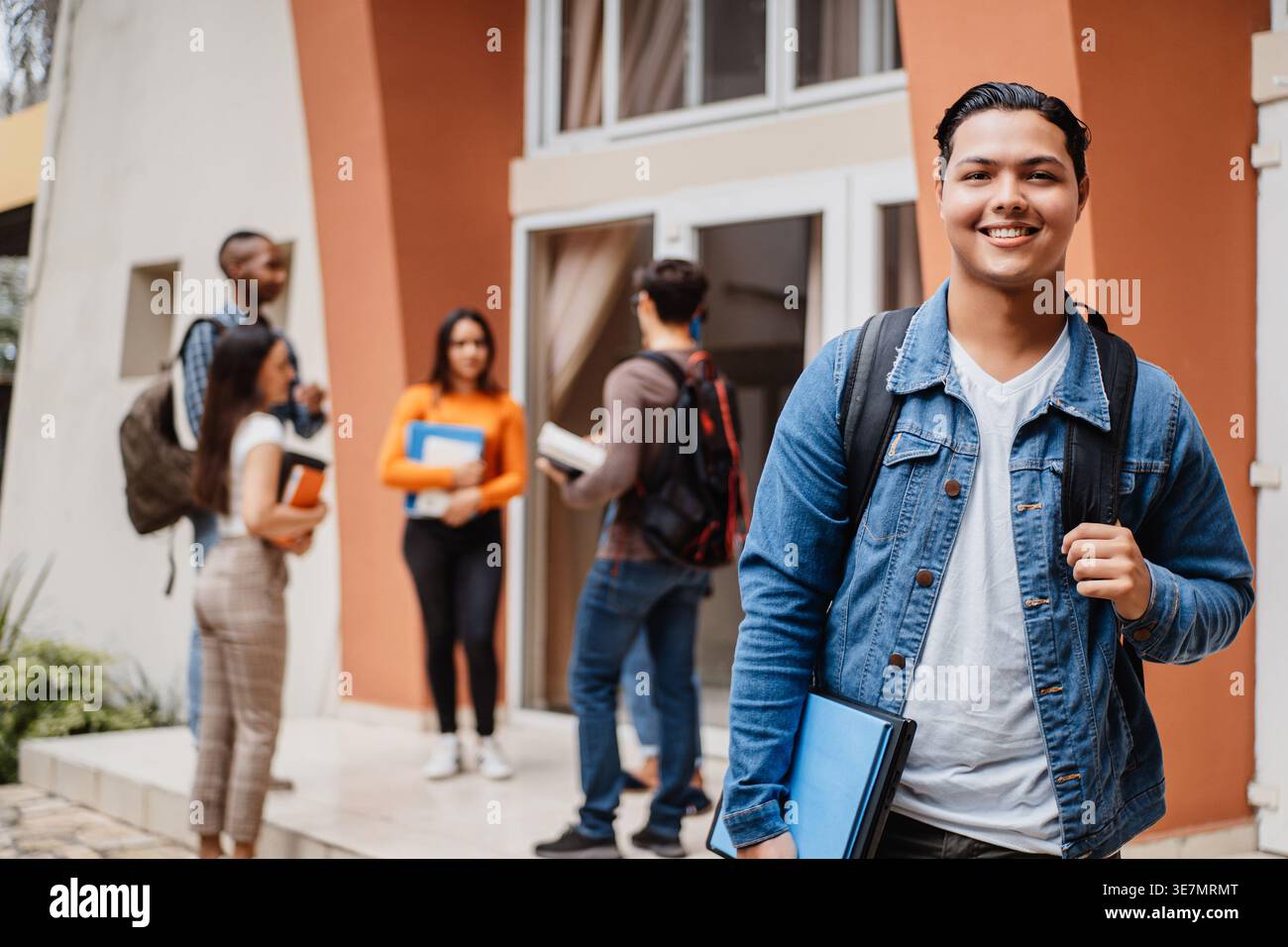 Étudiant hispanique avec sac à dos debout près de camarades de classe sur le campus Banque D'Images