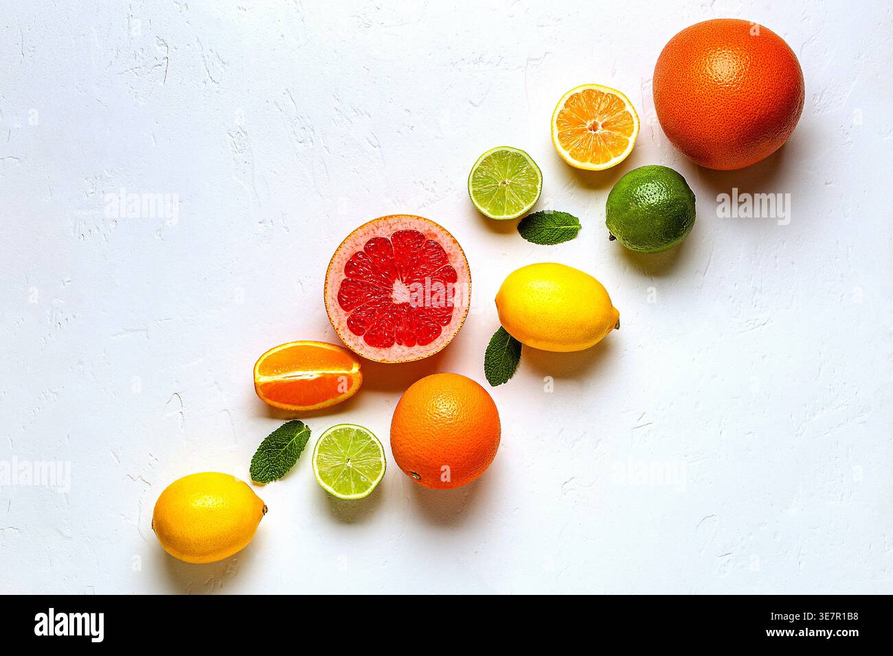 Citron frais, orange, pamplemousse, citron vert, feuilles vertes sur fond clair, vue de dessus. Concept de jus d'agrumes, vitamine C, fruits. Banque D'Images
