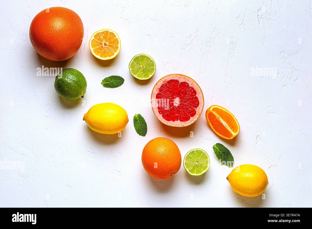 Citron frais, orange, pamplemousse, citron vert, feuilles vertes sur fond clair, vue de dessus. Concept de jus d'agrumes, vitamine C, fruits. Banque D'Images