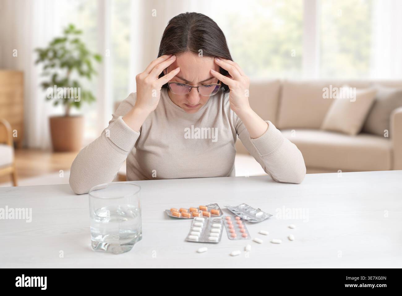 Femme stressée avec des maux de tête regardant plusieurs médicaments, confusion et concept de problème de santé Banque D'Images