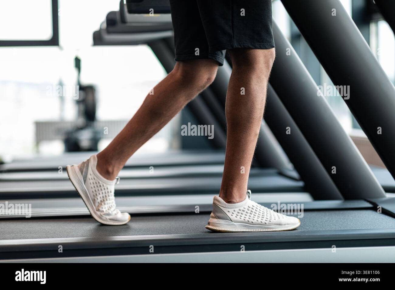 Image recadrée de Black Man jogging sur tapis roulant dans le gymnase Banque D'Images