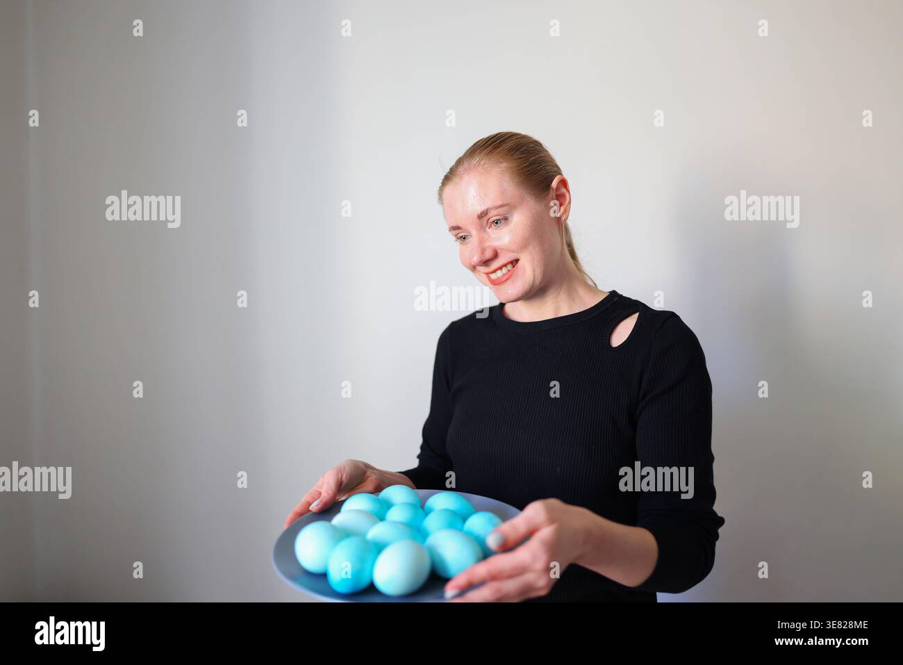 Femme souriante présentant des œufs colorés, célébration de Pâques et concept de tradition à la maison. Banque D'Images