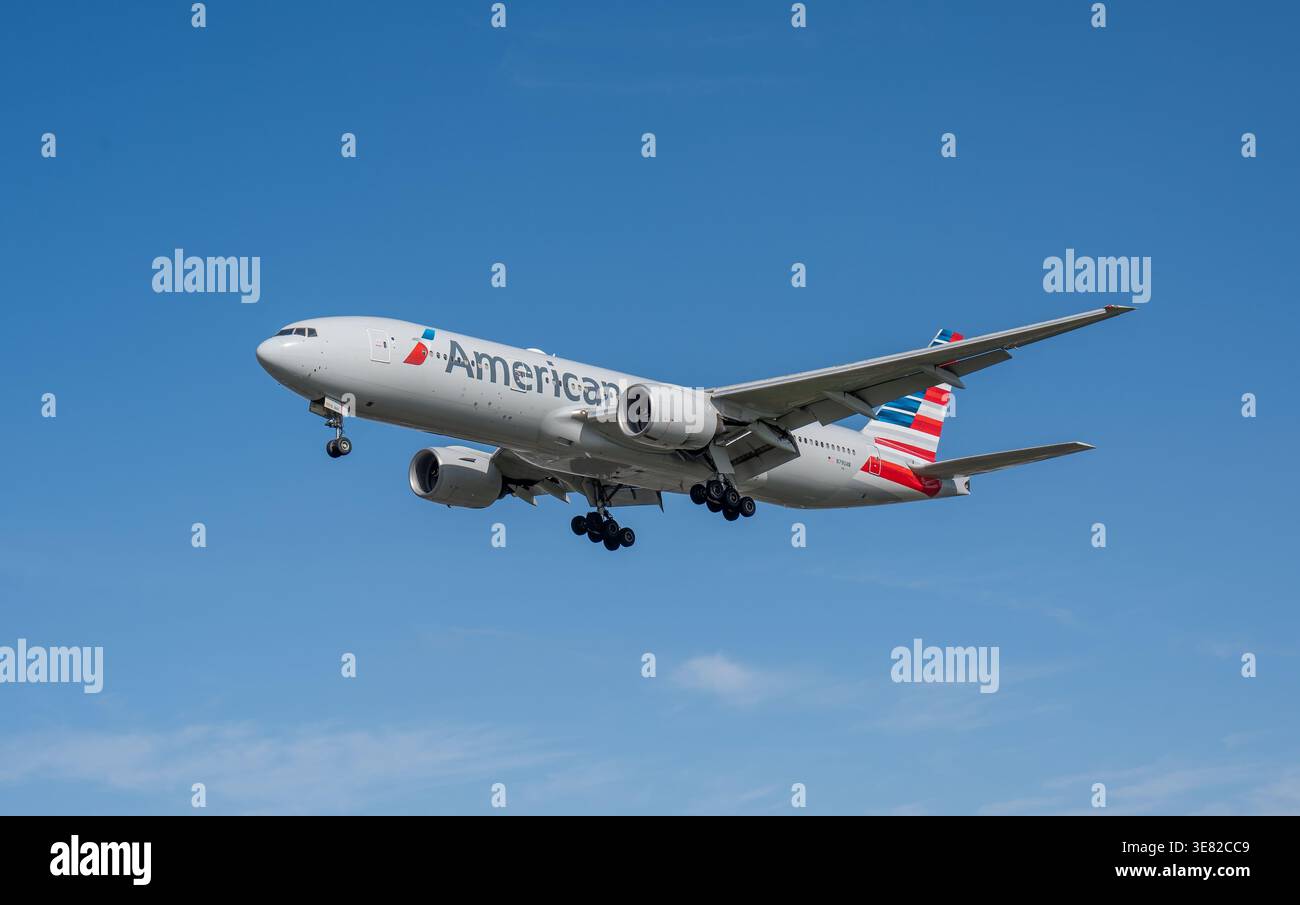 HEATHROW, Royaume-Uni, 17 MARS 2026 : atterrissage d'un Boeing 777-200 d'American Airlines en jet large contre un ciel bleu clair Banque D'Images