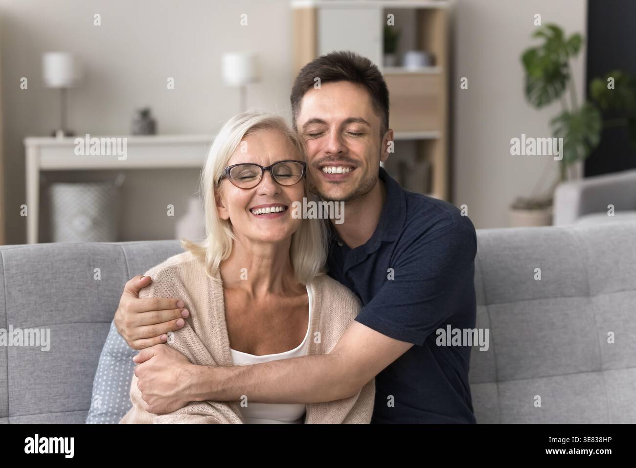 Aimant jeune homme adulte embrassant sa mère plus âgée souriante Banque D'Images