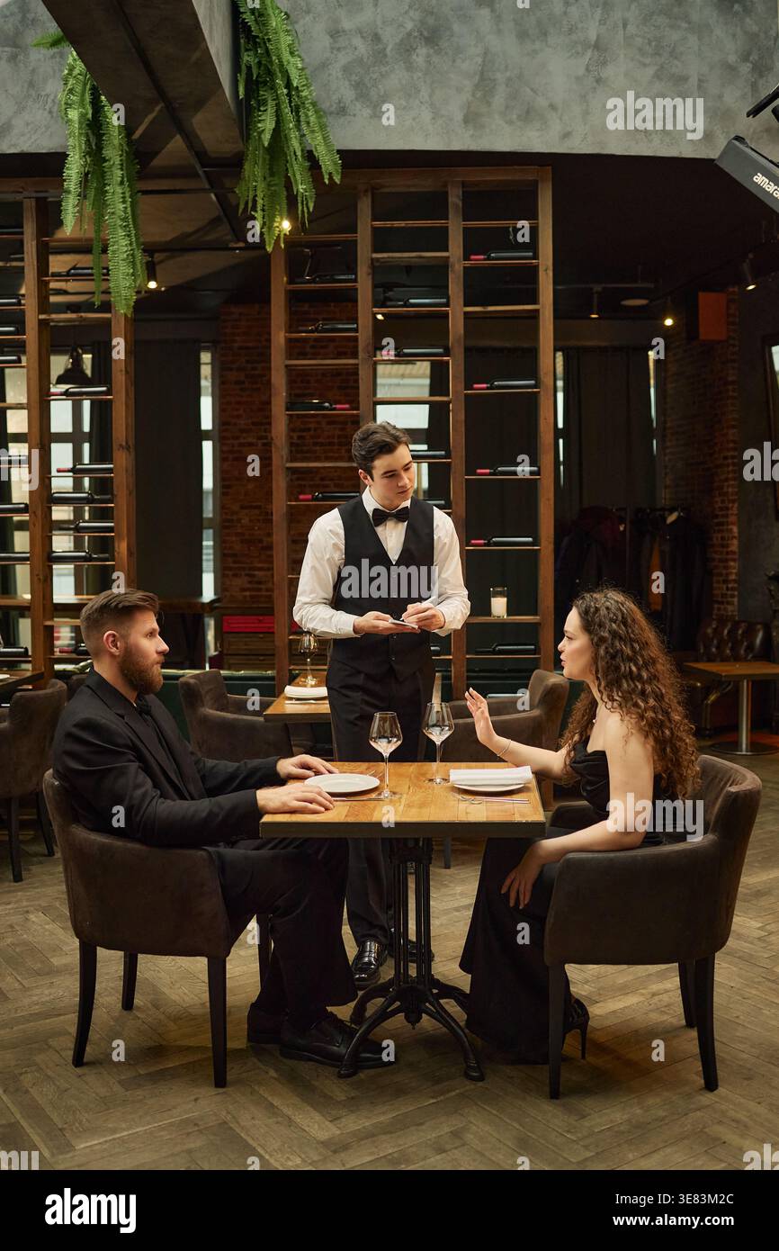 Couple adulte commandant un dîner auprès d'un serveur dans un restaurant haut de gamme Banque D'Images