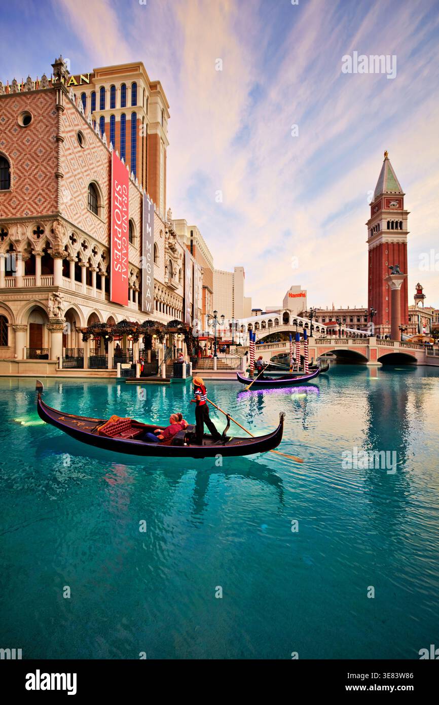 Les gondoles flottent sur l'eau devant le Venetian Hotel pendant le coucher du soleil à Las Vegas, Nevada. Les touristes apprécient la vue et la balade. Banque D'Images