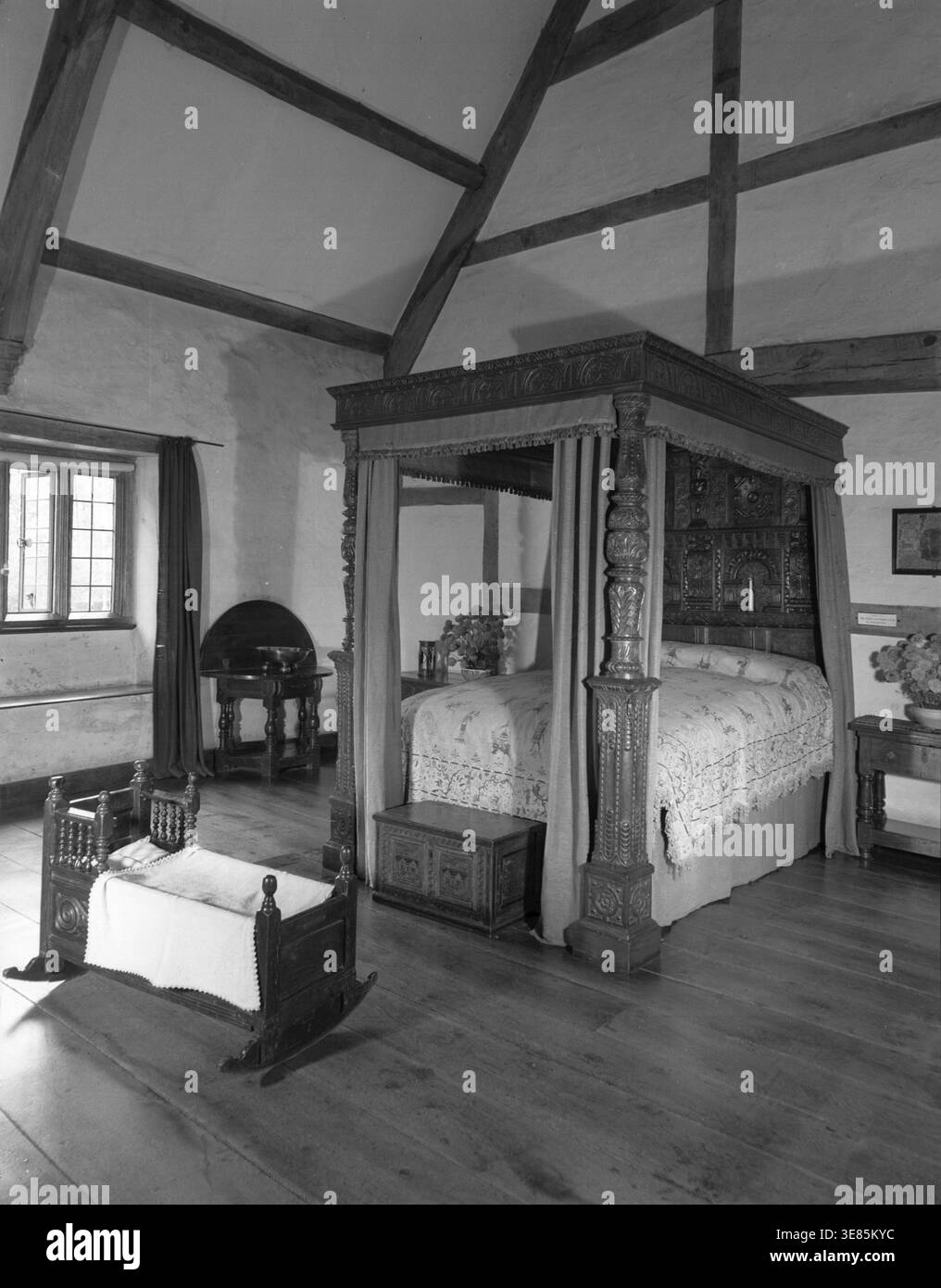 Sulgrave Manor, Northamptonshire, c1955. Pavillon Tudor du XVIe siècle construit par les ancêtres de George Washington. Lit à baldaquin en bois sculpté et berceau pour enfant. Banque D'Images