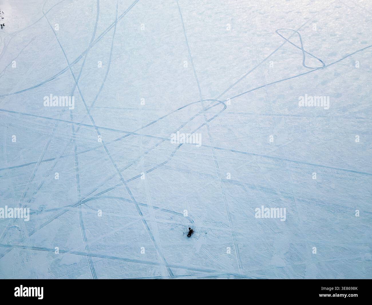 Vue aérienne minimaliste d'un large champ enneigé gravé de pistes sinueuses de ski et de skate, créant des lignes et des textures abstraites dans un finnois calme Banque D'Images