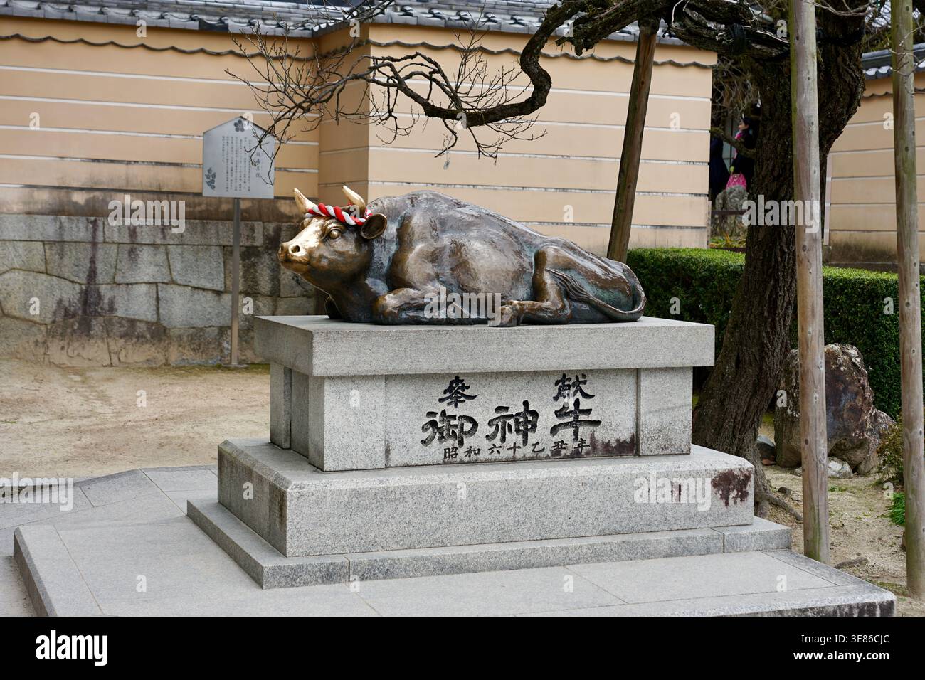 Statue de bœuf en bronze au sanctuaire japonais sur piédestal en pierre, sculpture religieuse traditionnelle au Japon Banque D'Images