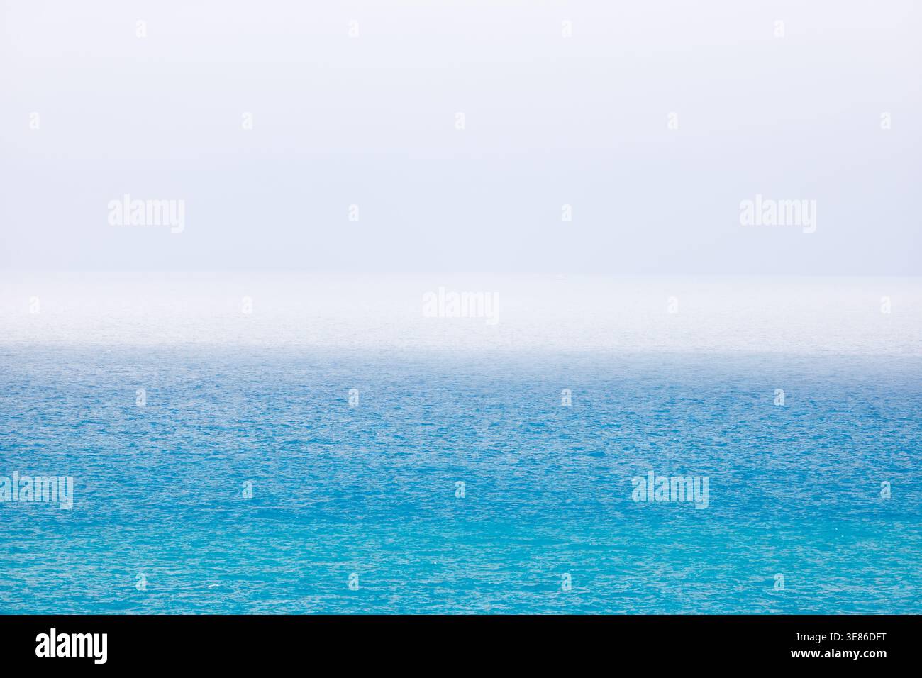 Ce paysage marin offre une vue épurée et minimaliste sur les eaux bleues de la Méditerranée près de Villajoyosa. Le ciel est lumineux et légèrement brumeux, mais avec les Banque D'Images