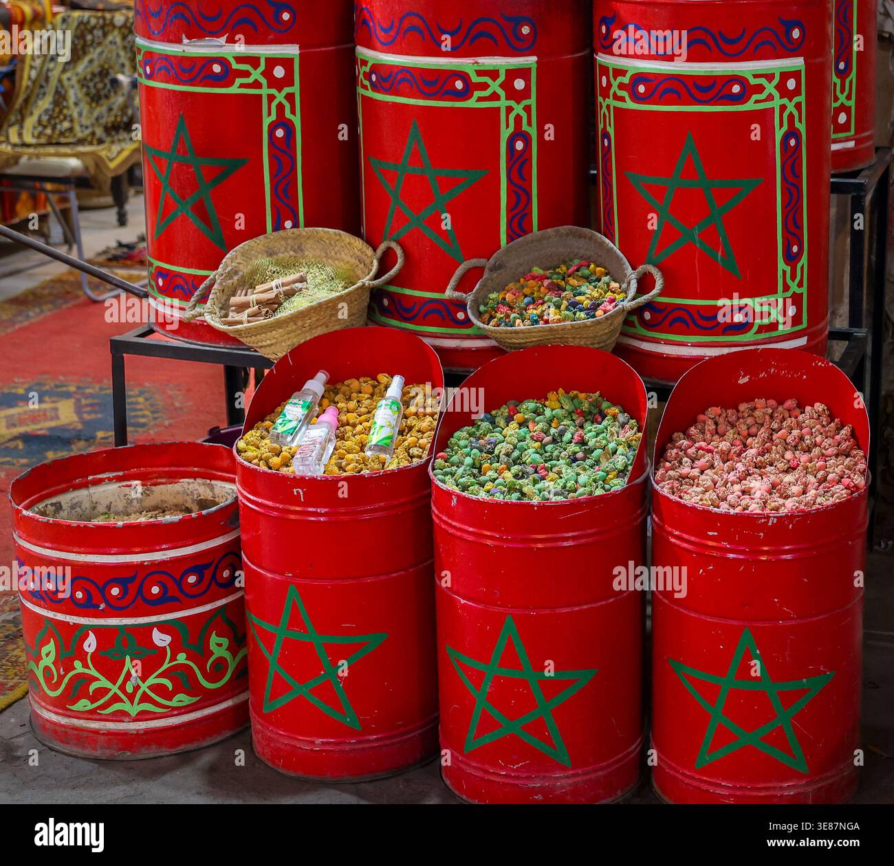 Présentation de marché à Marrakech de épices colorées, d'herbes séchées et de thés floraux dans de grandes boîtes en métal rouge décorées de l'étoile marocaine verte à cinq branches Banque D'Images