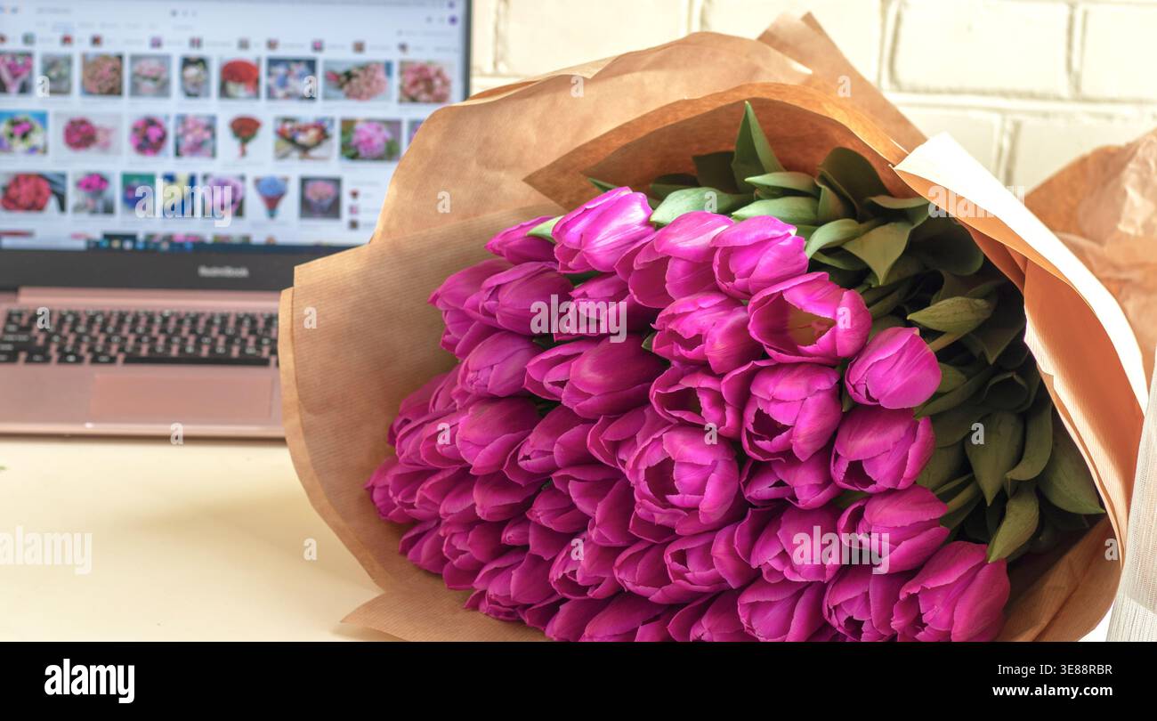un bouquet de fleurs sur la table sur la toile de fond d'un ordinateur portable. Banque D'Images