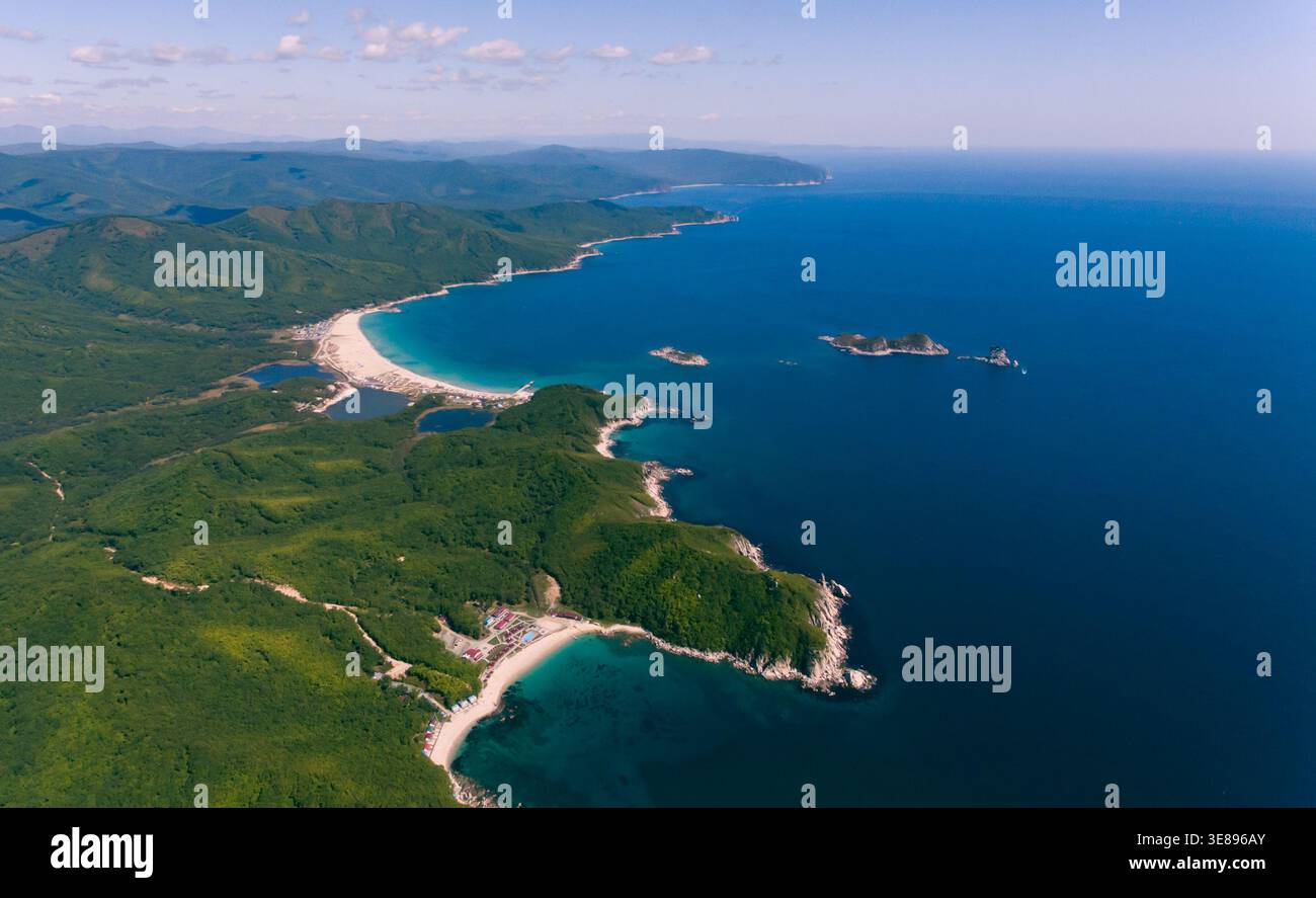 Panorama aérien d'un magnifique littoral avec une longue plage de sable blanc, des montagnes verdoyantes et une mer bleue calme. Banque D'Images
