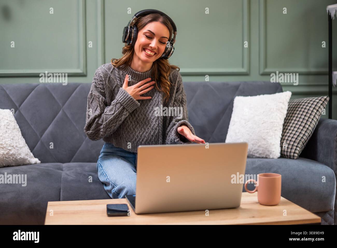 Femme ayant une conversation joyeuse sur son ordinateur portable. Elle est heureuse d'être connectée avec ses amis ou sa famille. Banque D'Images